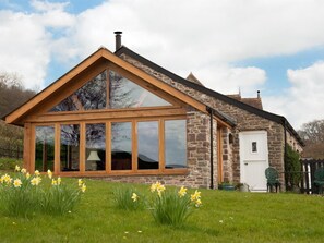 A stone house with a large glass bay window, a wooden gable roof, and a white door. - 1 Bed in Crickhowell (oc-bn198) (Crickhowell)