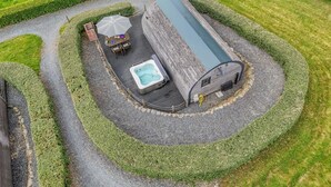 An aerial view of a spa area with a hot tub, a wooden structure, and a table with an umbrella.