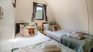 A cozy room with two beds, a window with curtains, a lamp, and towels.