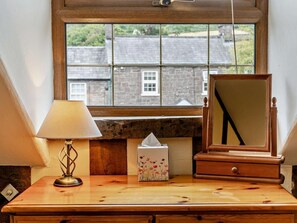 Ein hölzerner Kommode mit Lampe, Taschentuchbox und Spiegel.