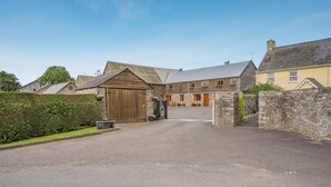 A rural street leading to a traditional stone building with a wooden gate, a stone wall, and a hedge. - 3 Bed in Brecon (oc-bn370) (Llyswen)
