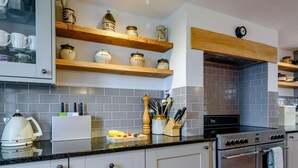 Eine moderne Küche mit weißen Schränken, Holzregalen und einem eingebauten Backofen.