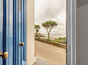 A coastal view with a stone pathway, palm trees, and a metal fence. - 1 Bed in Tenby (oc-fb021) (Tenby)
