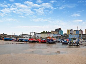A harbor with boats docked, buildings in the background, and a clear sky. - 1 Bed in Tenby (oc-fb021) (Tenby)