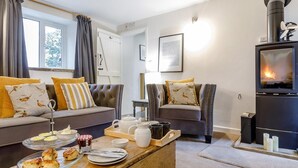 Ein gemütliches Wohnzimmer mit Kamin, Sofas und einem Couchtisch mit Gebäck.