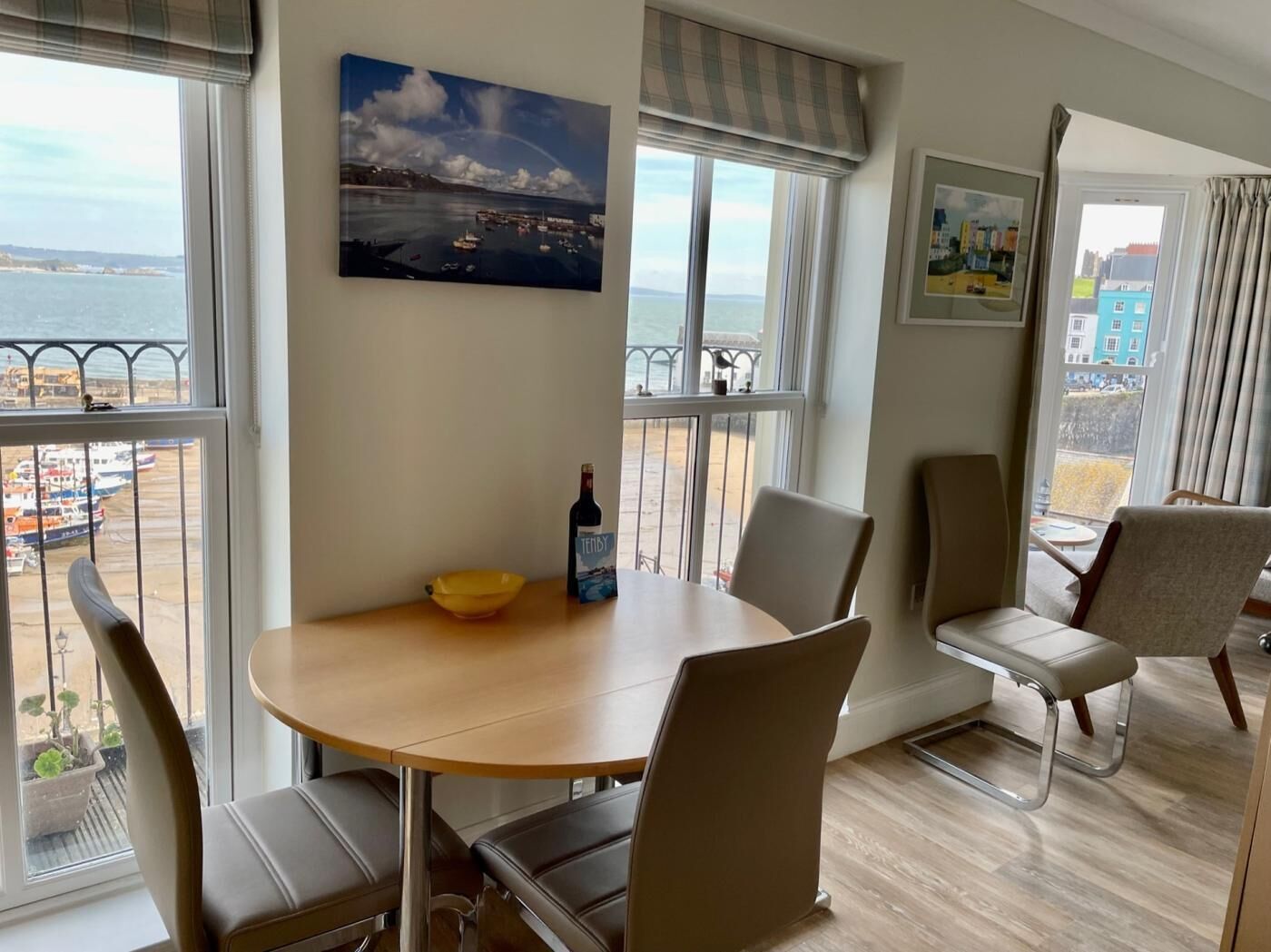 A dining area with a table, chairs, a bowl, and a bottle.