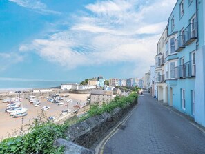 A coastal street with buildings, a beach, and boats. - 2 Bed in Tenby (oc-fb114) (Tenby)
