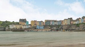 A coastal town with colorful buildings, a sandy beach, and boats docked near the shore. - 2 Bed in Tenby (oc-fb110) (Tenby)