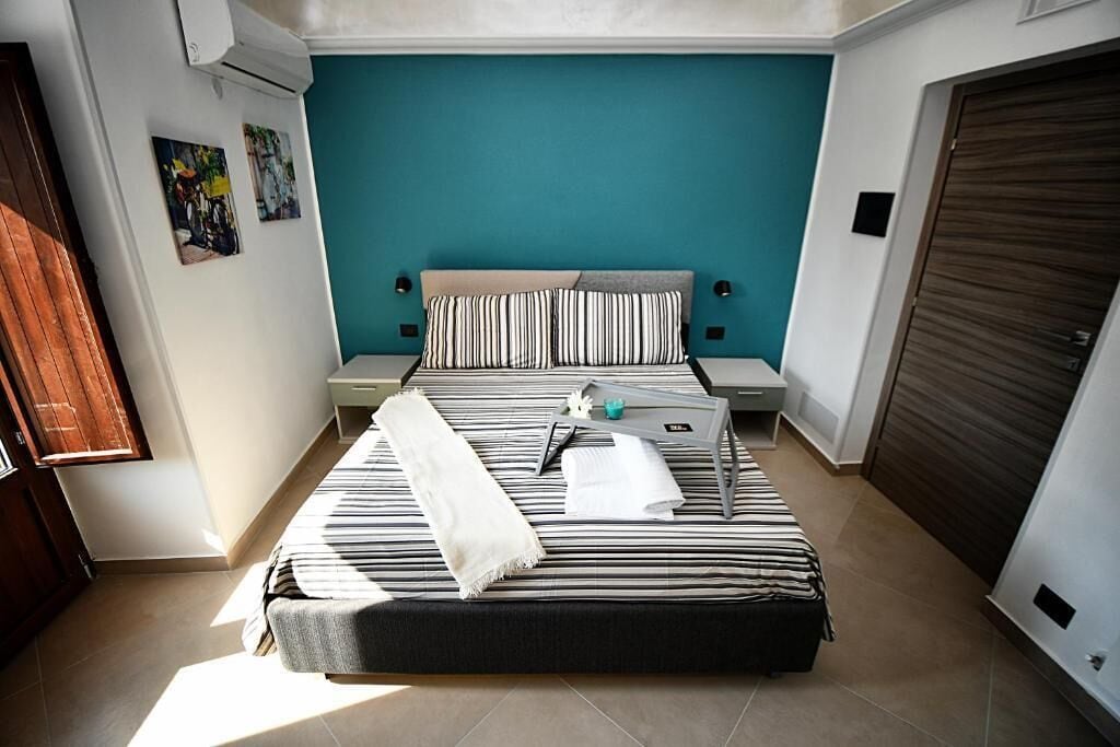 A bedroom with a bed, bedside tables, a window, and a door.