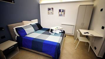 Un dormitorio con cama, mesita de noche, silla, escritorio y armario.