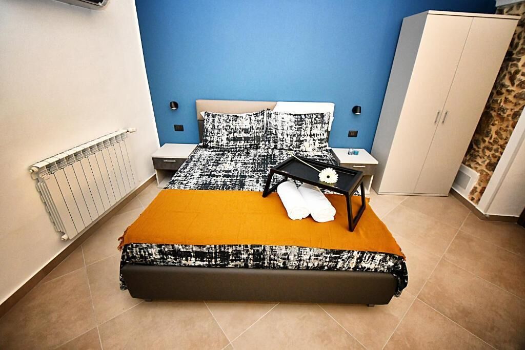 A bedroom with a bed, a nightstand, a wardrobe, and a radiator.