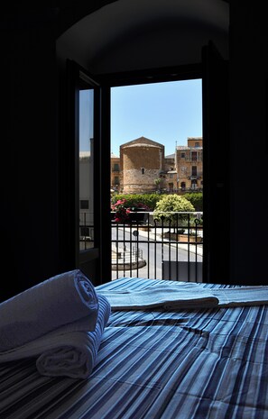 Una habitación con cama, ventana y vistas a edificios y zonas verdes.