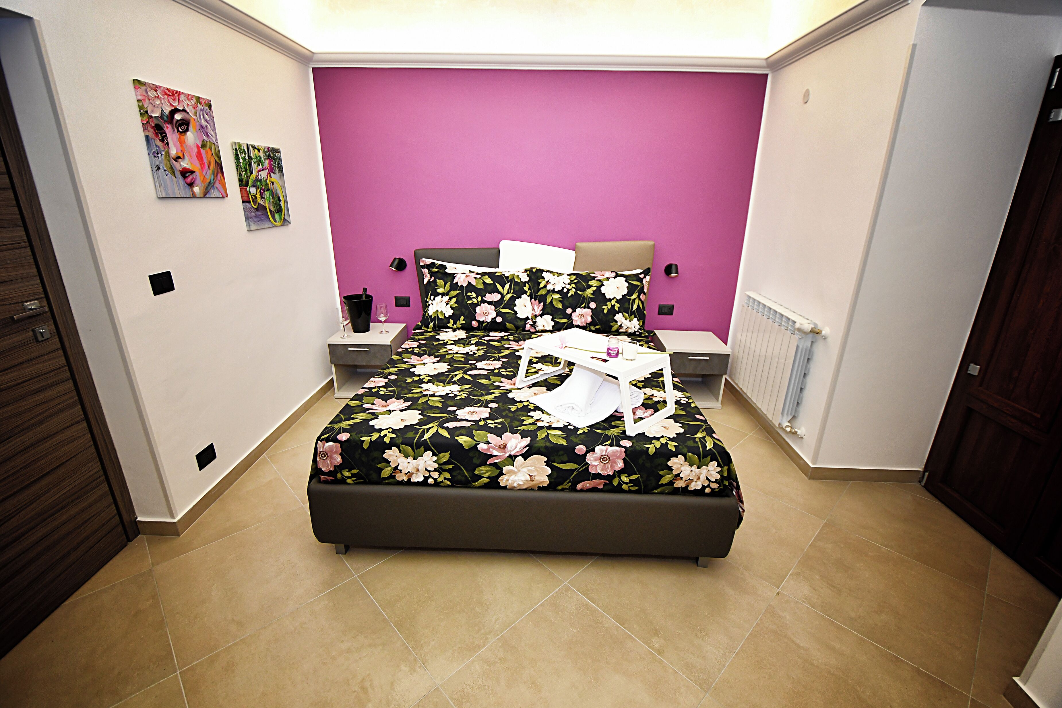 Una camera da letto con un letto, comodini, un radiatore e opere d'arte alle pareti.