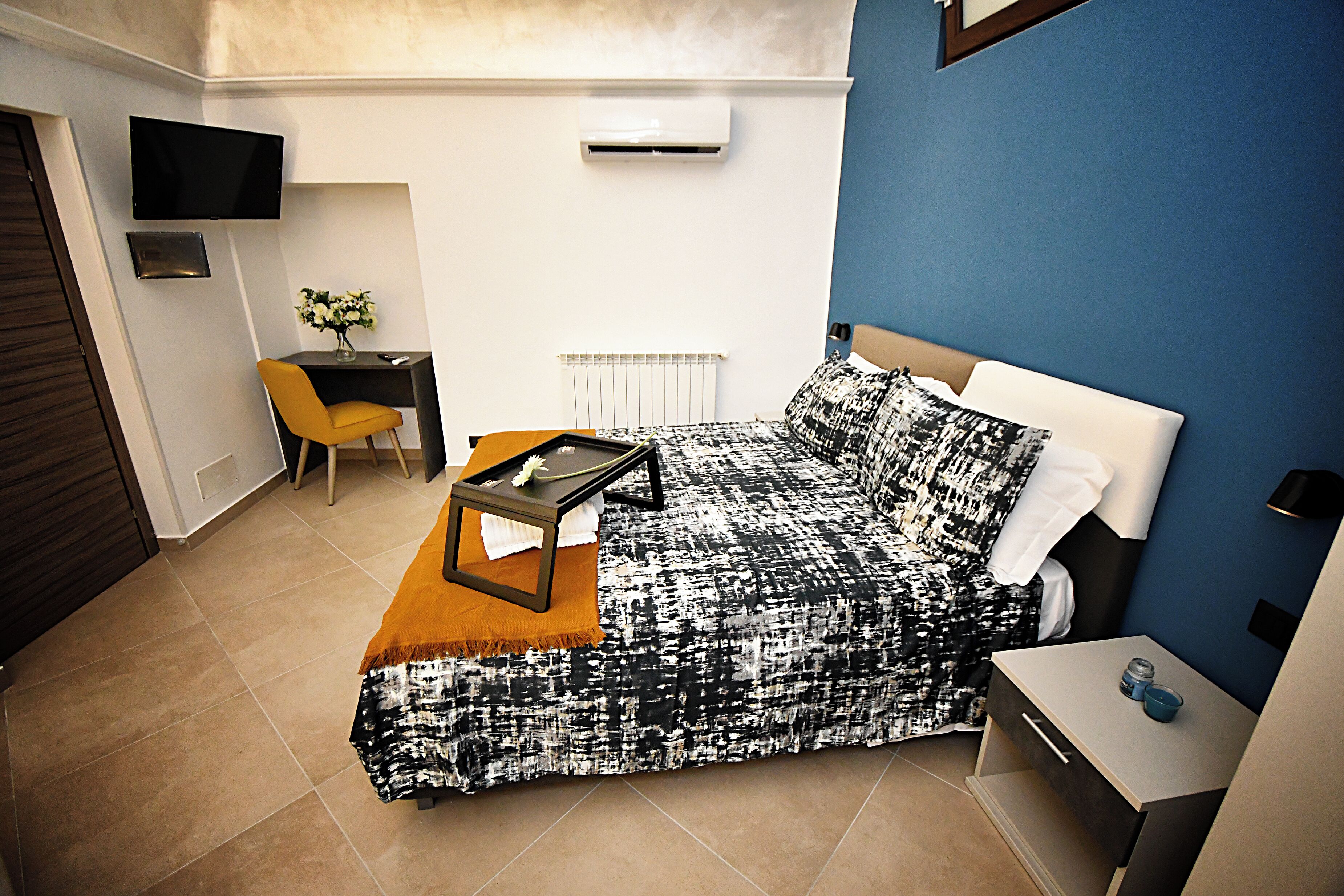 A bedroom with a bed, a desk, a chair, and a TV.