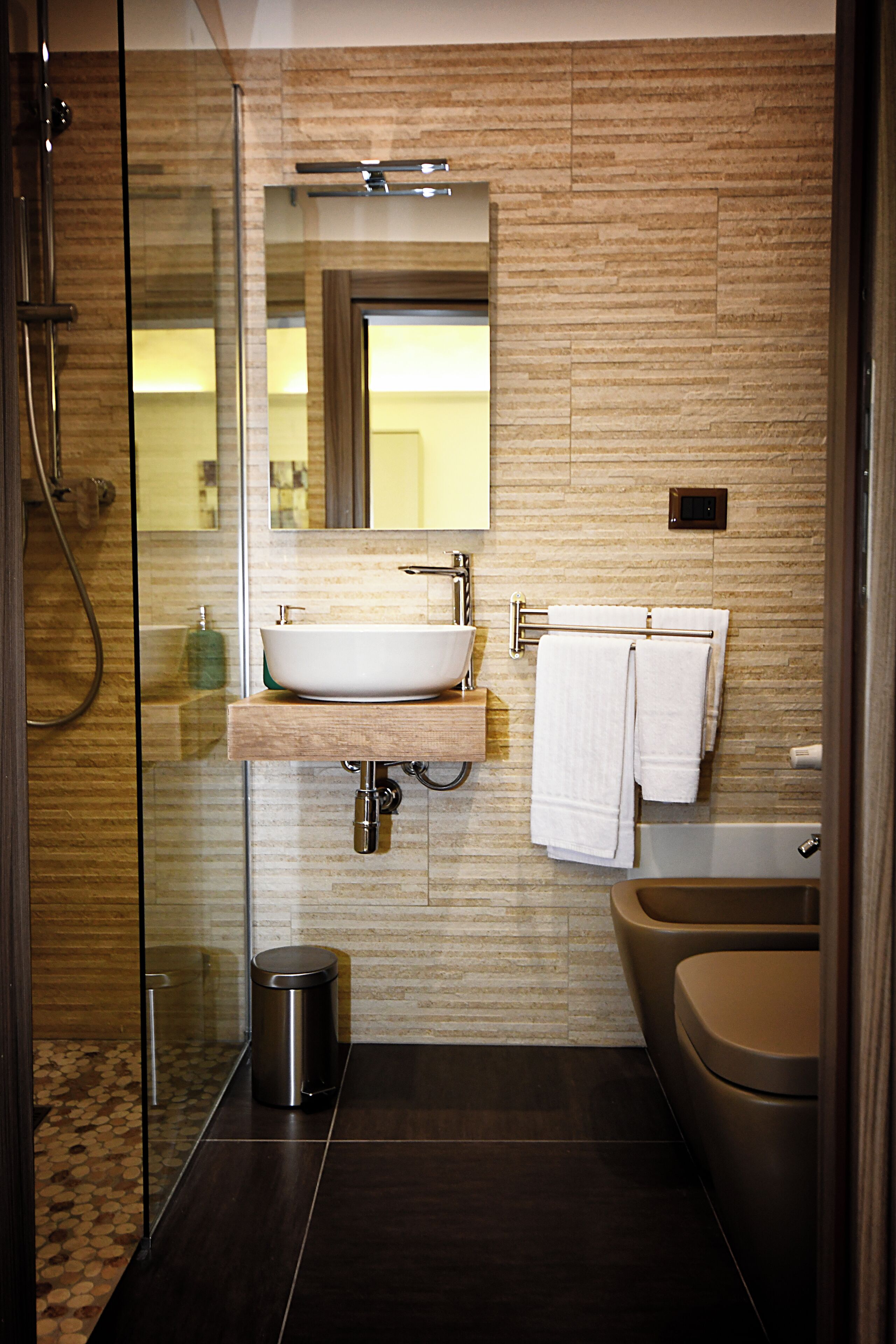 Ein modernes Badezimmer mit Duschkabine aus Glas, einem Aufsatzbecken, einem Waschtisch, einer Badewanne und einer Toilette.