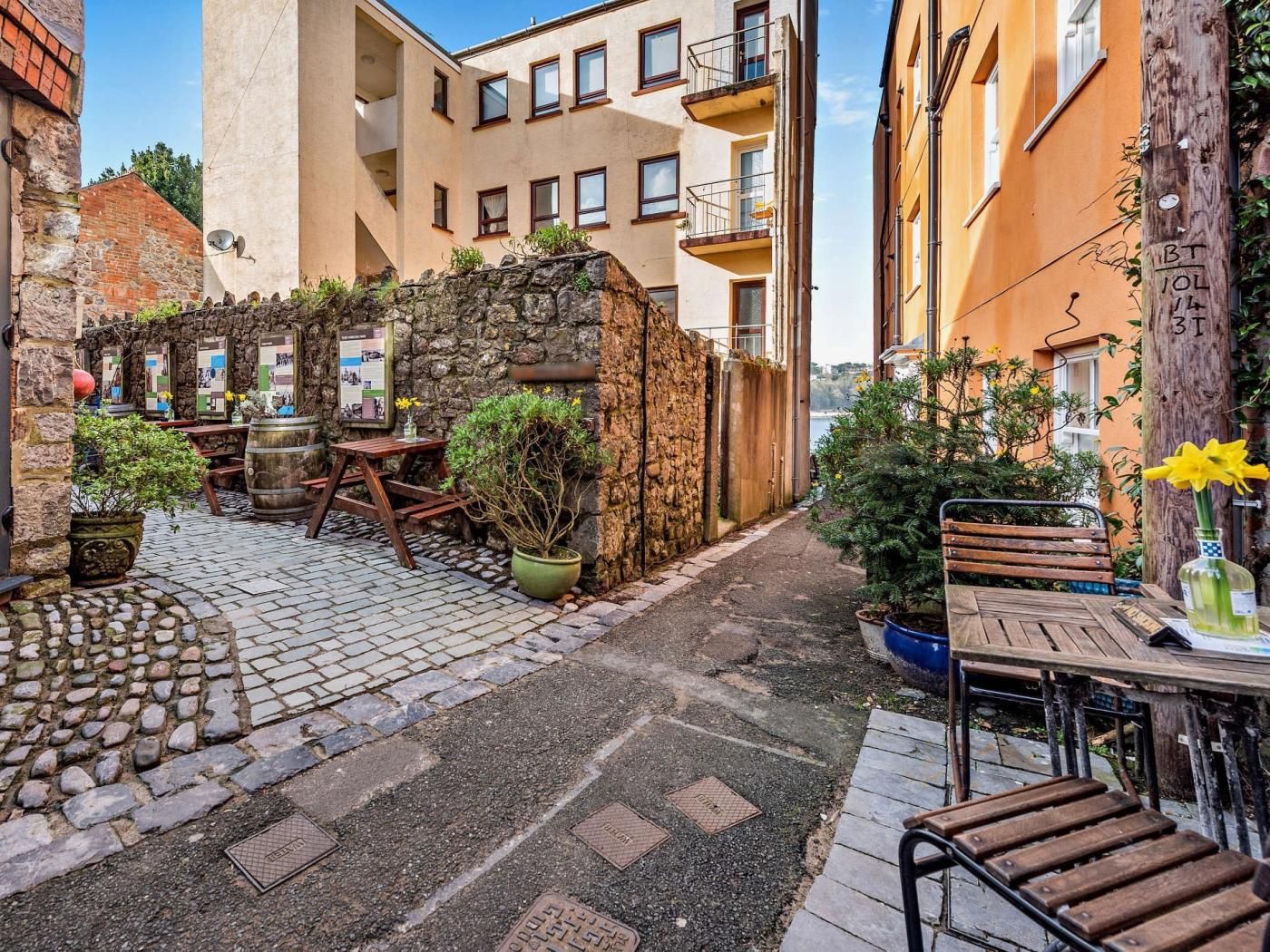 A courtyard with stone paving, outdoor seating, and potted plants.