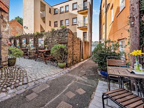 Ein Innenhof mit Steinpflasterung, Sitzgelegenheiten und Kübelpflanzen.