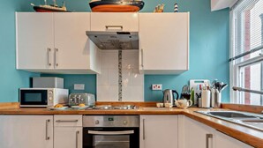 A modern kitchen with white cabinets, a stainless steel oven, a microwave, and a toaster. - 2 Bed in Tenby (oc-fb122) (Tenby)