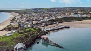 A coastal town with colorful buildings, a beach, and a pier. - 2 Bed in Tenby (oc-fb122) (Tenby)