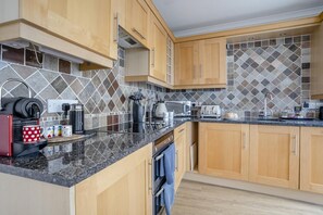 Eine moderne Küche mit Holzschränken, einer gefliesten Spritzschutzleiste und verschiedenen Geräten, darunter eine Kaffeemaschine und ein Toaster.
