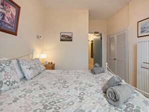 A bedroom with a bed, pillows, a nightstand, a lamp, a framed picture, and a closet. - 2 Bed in Tenby (oc-fb124) (Tenby)