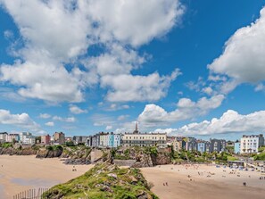 A coastal town with a sandy beach, colorful buildings, and a prominent church steeple. - 2 Bed in Tenby (oc-fb124) (Tenby)