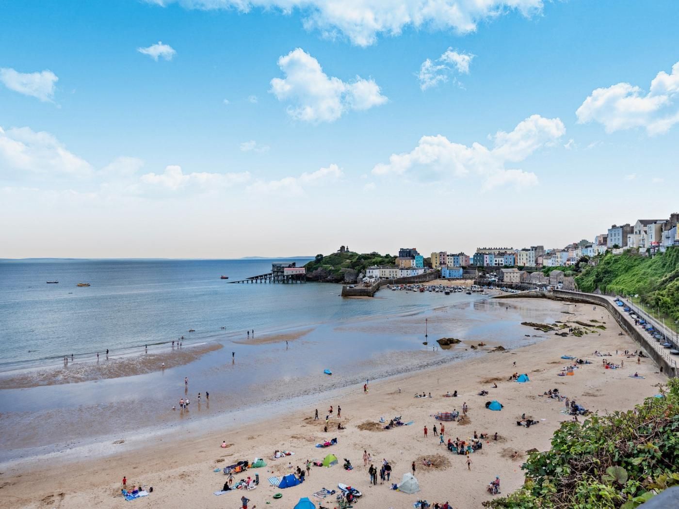 A beach with people, tents, and a pier.