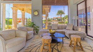 A spacious living room with a large window, a sofa, a coffee table, and a decorative bowl. - Diamante 91 (Noord)