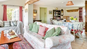 Ein gemütliches Wohnzimmer mit einer Couch, einem Esstisch und einer Holzbalkendecke.