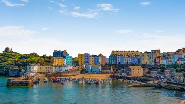 A coastal town with colorful buildings, a harbor with boats, and a historic castle on a hill. - 1 Bed in Tenby (oc-fb162) (Tenby)