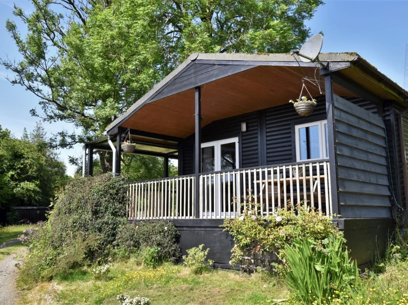 Une cabane en bois avec une véranda, une antenne parabolique et un panier suspendu.