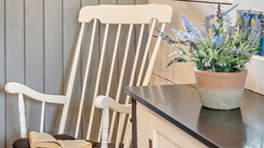 A white wooden chair with a cushion, a potted plant, and a kitchen counter. - 2 Bed in Abergavenny (oc-bn246) (Pantygelli)