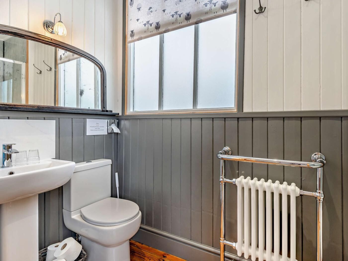 Une salle de bain avec un lavabo, des toilettes et un radiateur, le tout de couleur blanche.