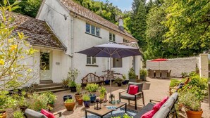 Ein weißes Haus mit Ziegeldach, einer Terrasse mit Gartenmöbeln und Pflanzkübeln.