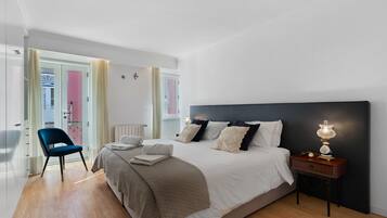 A bedroom with a bed, bedside table, lamp, and a chair.