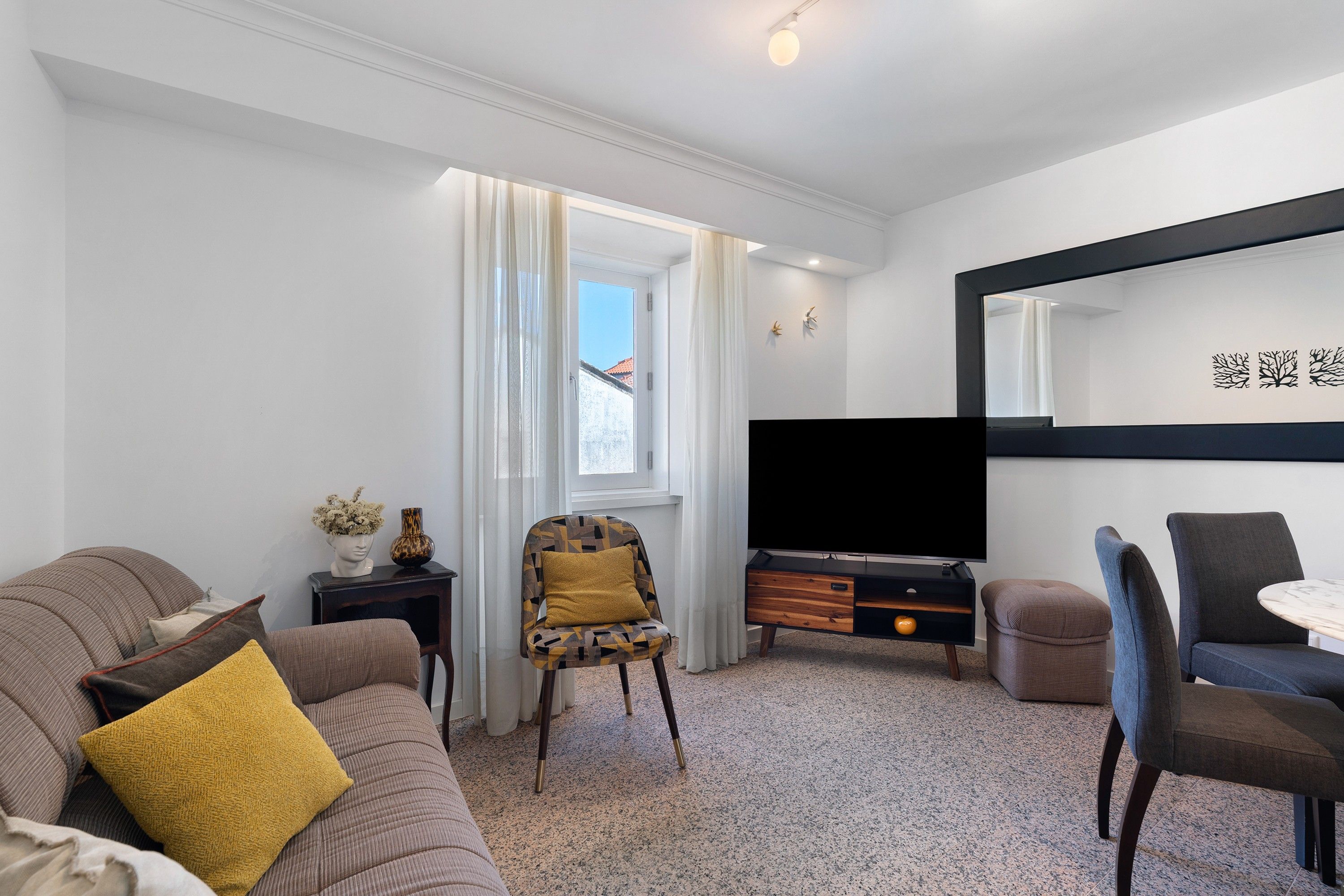 Ett modernt vardagsrum med en soffa, fåtölj, TV och en matplats.