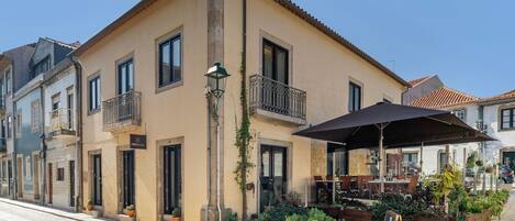 A building with a balcony, outdoor seating, and potted plants.