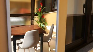 A room with a dining table, chairs, a vase with flowers, and a window with a view. - Casa de São Roque 1 – Beachfront Apartment for 6 Guests (Vila do Conde)