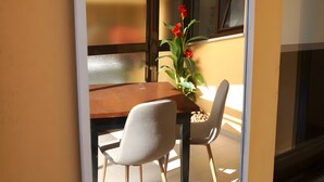 A room with a wooden dining table, two chairs, and a vase with red flowers. - Casa de São Roque 1 – Beachfront Apartment for 6 Guests (Vila do Conde)