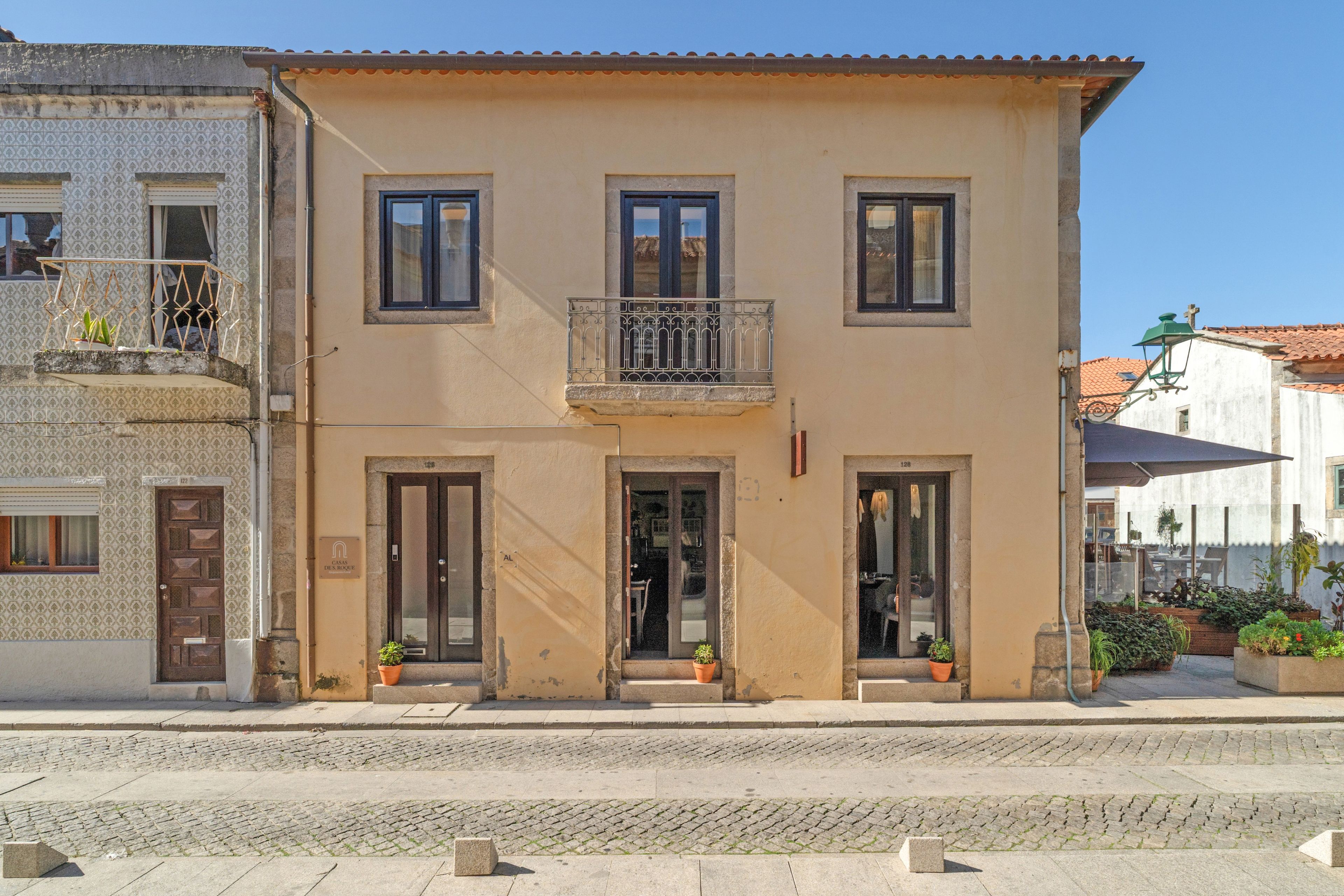 A two-story building with a balcony, a door, and a window.