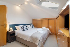 Un dormitorio con cama, mesita de noche, lámpara y televisión.
