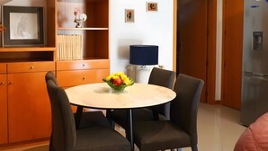 Una cocina compacta con mesa, sillas, refrigerador y un mueble de madera.