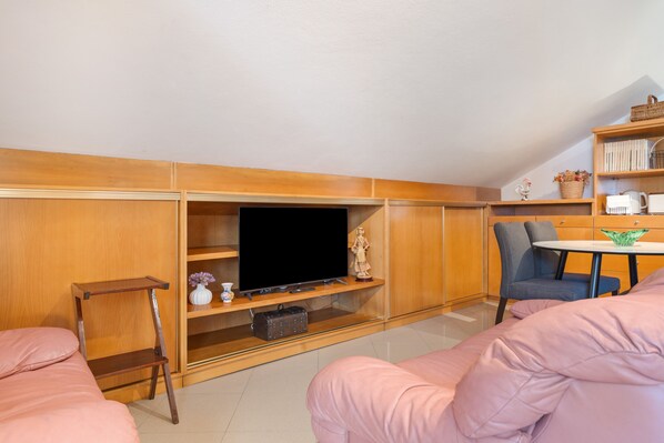 Una sala de estar acogedora con un televisor de pantalla plana, armarios de madera, una mesita y una silla.
