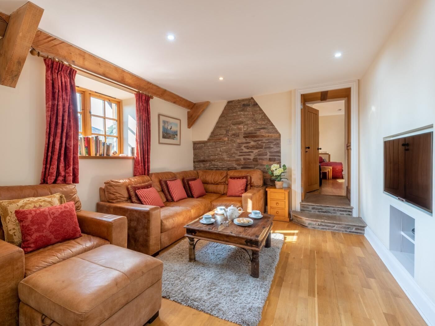 A cozy living room with a stone fireplace, leather sofas, and a wooden coffee table.