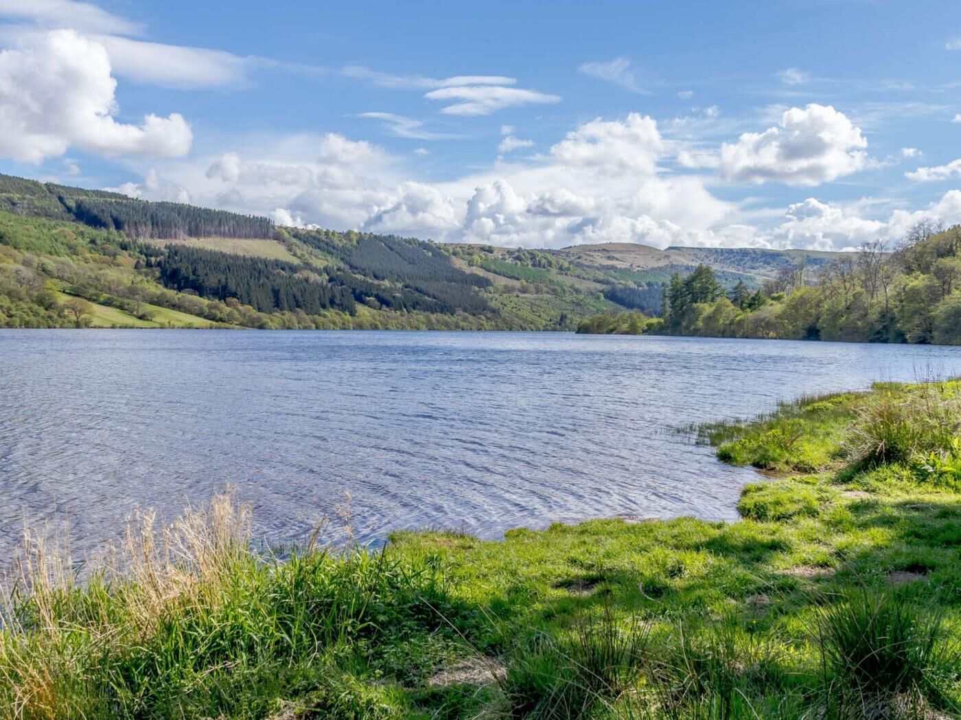A lake surrounded by green hills and trees.