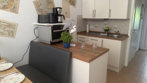 Een kleine keuken met een eethoek, voorzien van een koffiezetapparaat, een plant en een kaart aan de wand.