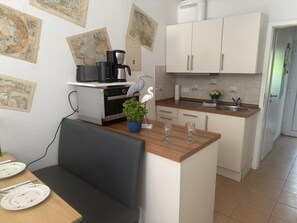 Eine kompakte Küche mit Essbereich, ausgestattet mit einer Kaffeemaschine, einer Pflanze und einer Karte an der Wand.