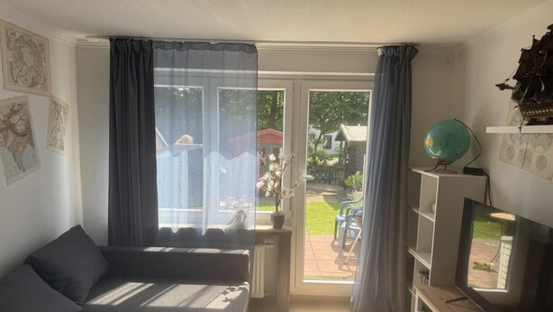 Een woonkamer met een bank, een televisie en uitzicht.