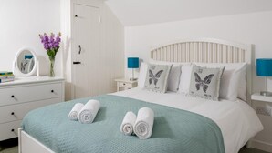 Une chambre à coucher comprenant un lit, deux tables de chevet, une commode, une coiffeuse, un miroir et un vase avec des fleurs.