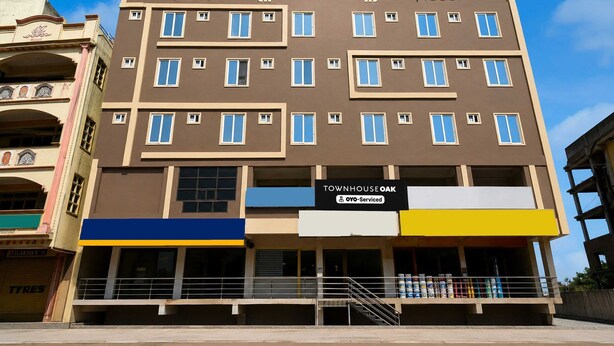 Monikerroksinen rakennus, jossa on kyltti, jossa lukee ”TOWNHOUSE OAK” ja ”OYO-Serviced”, mikä viittaa siihen, että rakennuksessa on palveluhuoneistoja.